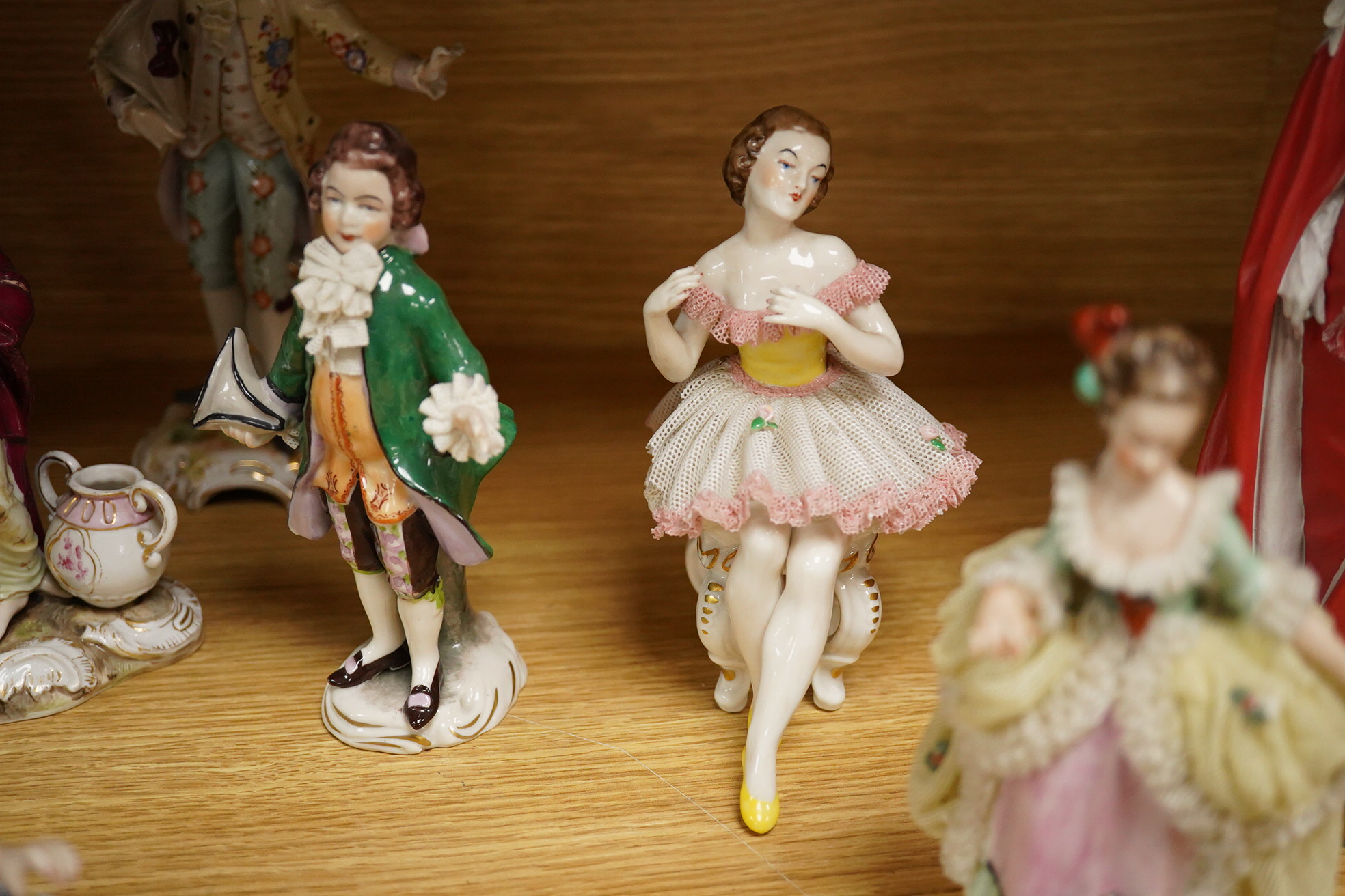 Nine continental figurines, to include Dresden porcelain lace examples, together with a resin figurine of Queen Elizabeth, largest 23cm high